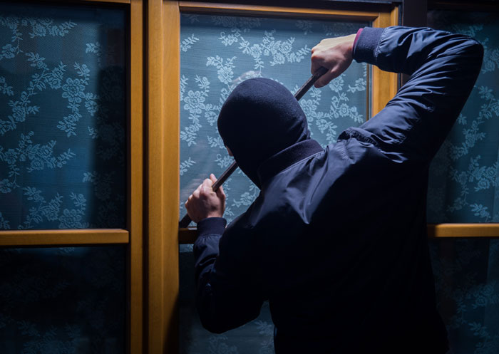 Ansicht Mann von hinten bricht in ein Glasfenster ein 