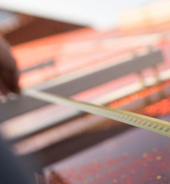 gelbes Maßband vor rot schimmernder Folie