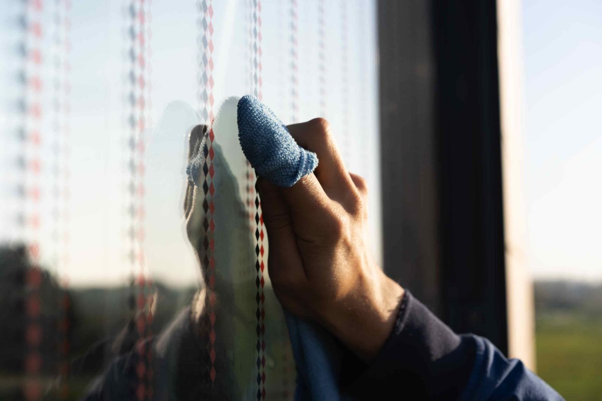 Hand mit Microfasertuch bei der Montage der Vogelschutzfolie